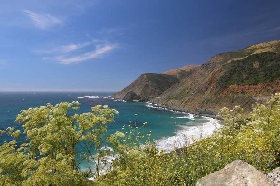 Hills rise up from the ocean as the Pacific Coast Highway curves round the turquoise water.